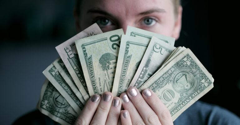 Things to Do When Seeking a Professional Voice Over - Woman holds Dollar bills