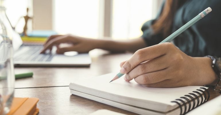 Dubbing-A Comprehensive Guide - woman writes on notepad while using laptop