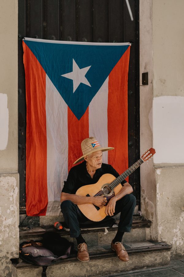 Puerto Rican Spanish voice actors - old man plays guitar with puerto rican flag behind